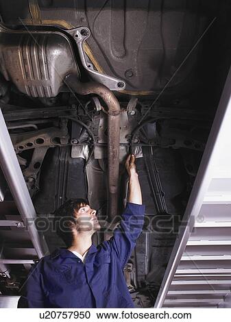 Mechanic standing under raised car View Large Photo Image Stock Image - Mechanic standing under raised car. Fotosearch