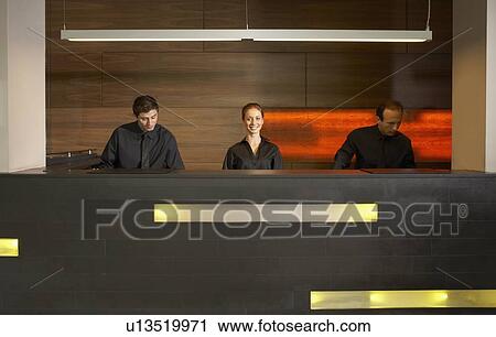 Stock Image - Staff at reception in hotel lobby. Fotosearch