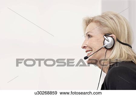 Woman smiling on headset View Large Photo Image Stock Photo - Woman smiling on headset. Fotosearch