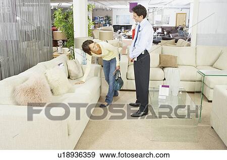 Stock Photo - Woman talking to salesman in sofa shop.. Fotosearch