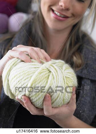 Stock Photograph - Young woman holding ball of wool, smiling, close-up. Fotosearch