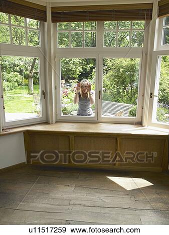Blond woman looking through window into empty room. View Large Photo Image Stock Photo - Blond woman looking through window into empty room.. Fotosearch