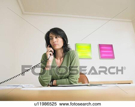 Concerned businesswoman at her desk giving a call. View Large Photo Image Stock Photography - Concerned businesswoman at her desk giving a call.. Fotosearch