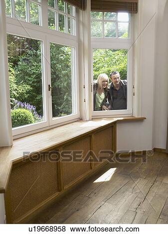 Stock Photo - Couple looking through window into empty room. Wide angle.. Fotosearch
