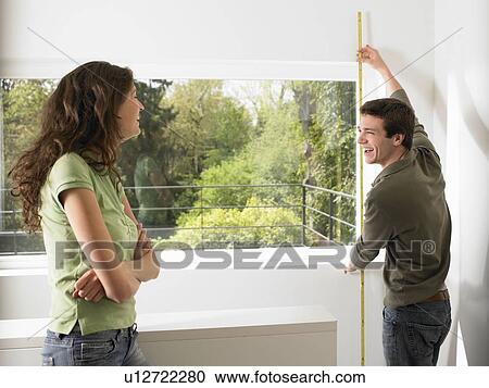 Stock Image - Couple taking measurement of their home. Fotosearch