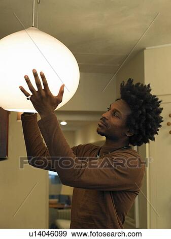 Man adjusting ceiling light in room View Large Photo Image Stock Photo - Man adjusting ceiling light in room. Fotosearch