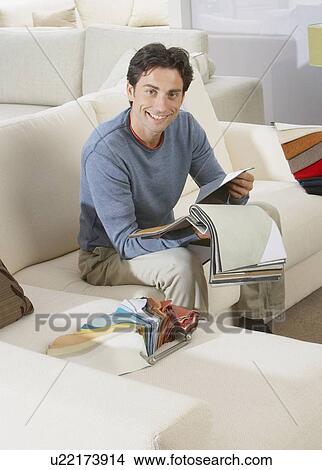 Picture - Man sitting on sofa in furniture store.. Fotosearch
