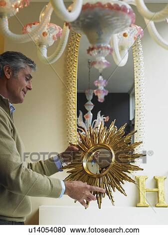 Mature man holding up mirror in shop, smiling View Large Photo Image Stock Image - Mature man holding up mirror in shop, smiling. Fotosearch