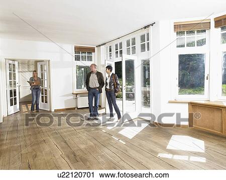 Stock Image - Real estate agent showing empty house to a couple.. Fotosearch