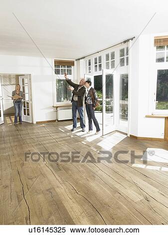 Stock Photography - Real estate agent showing empty house to couple.. Fotosearch