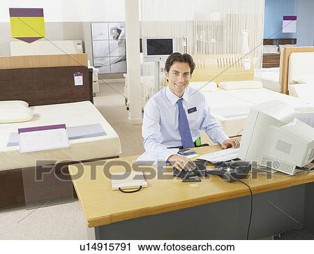 Stock Image - Salesman sitting at a desk.. Fotosearch