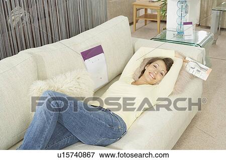 Stock Photo - Woman lying on sofa in furniture store.. Fotosearch