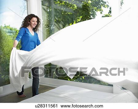 Stock Image - Woman making her bed. Fotosearch