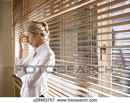 Woman standing by the window View Large Photo Image Stock Photo - Woman standing by the window. Fotosearch