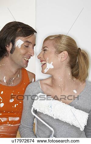 Young couple holding paint rollers face to face, smiling View Large Photo Image Picture - Young couple holding paint rollers face to face, smiling. Fotosearch