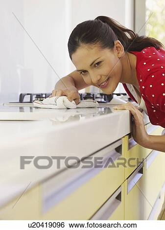 Young woman cleaning kitchen surface View Large Photo Image Stock Photograph - Young woman cleaning kitchen surface. Fotosearch
