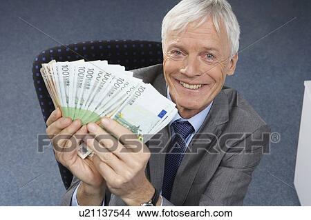 Businessman holding money, smiling View Large Photo Image Picture - Businessman holding money, smiling. Fotosearch