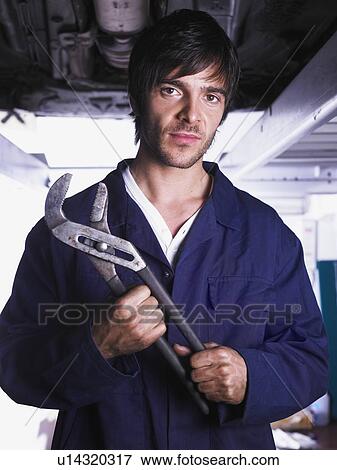 Mechanic under a raised car View Large Photo Image Stock Photo - Mechanic under a raised car. Fotosearch