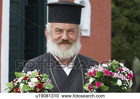 Old priest in front of church holding two bunches of flowers looking into camera smiling. View Large Photo Image Stock Image - Old priest in front of church holding two bunches of flowers looking into camera smiling.. Fotosearch