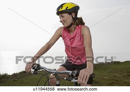 Stock Photo - A Woman sitting on a bicycle.. Fotosearch