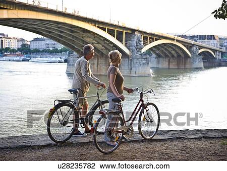 Couple by river with bikes View Large Photo Image Stock Image - Couple by river with bikes. Fotosearch