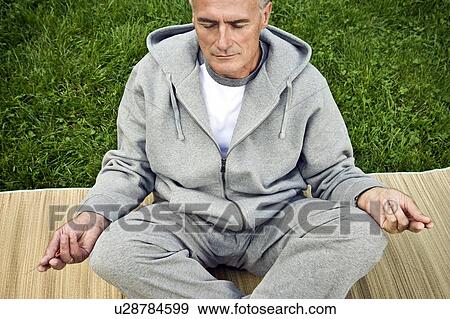 Man meditating seated on grass View Large Photo Image Stock Photo - Man meditating seated on grass. Fotosearch
