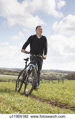 Man pushing a bike in the country View Large Photo Image Stock Image - Man pushing a bike in the country. Fotosearch