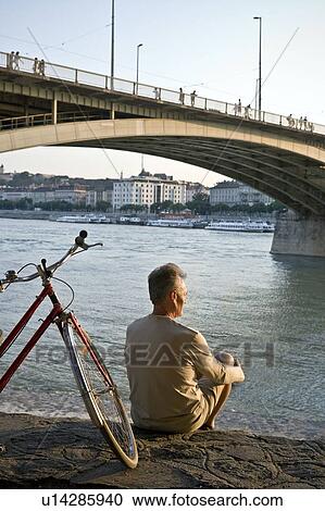 Man sitting alone by river View Large Photo Image Stock Image - Man sitting alone by river. Fotosearch