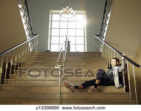 Stock Image - Mature man sitting on steps, low angle view. Fotosearch