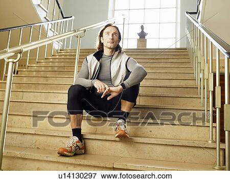 Stock Photo - Mature man sitting on steps, low angle view. Fotosearch