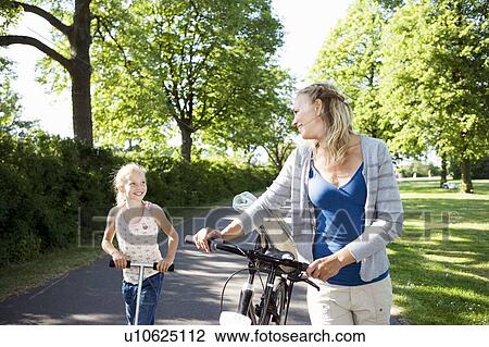 Stock Image - Mother and daughter with bike. Fotosearch