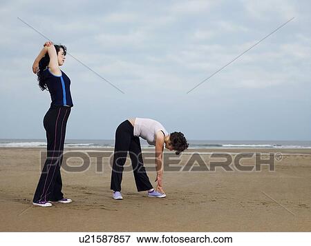 Stock Photo - Two young females stretching on beach. Fotosearch