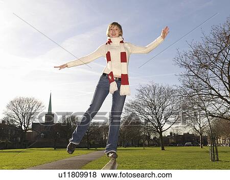 Stock Photo - Woman balancing on bench in park. Fotosearch