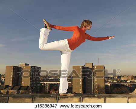 Stock Photo - Woman balancing on roof terrace. Fotosearch
