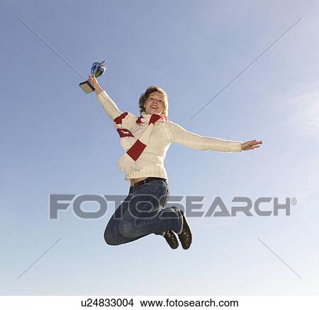Woman jumping, holding trophy View Large Photo Image Picture - Woman jumping, holding trophy. Fotosearch