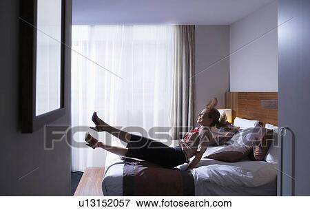 Stock Photo - Woman jumping onto bed. Fotosearch