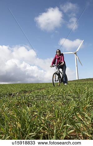 Woman riding a bike on a wind farm View Large Photo Image Stock Image - Woman riding a bike on a wind farm. Fotosearch