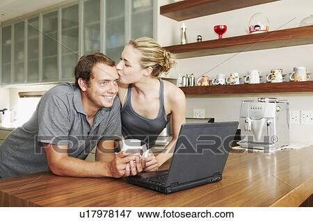 Couple in kitchen, woman kisses partner View Large Photo Image Stock Photo - Couple in kitchen, woman kisses partner. Fotosearch