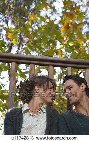 Stock Image - Couple outdoors on balcony sitting together and smiling.. Fotosearch