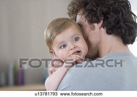 Stock Image - Father cuddles baby. Fotosearch