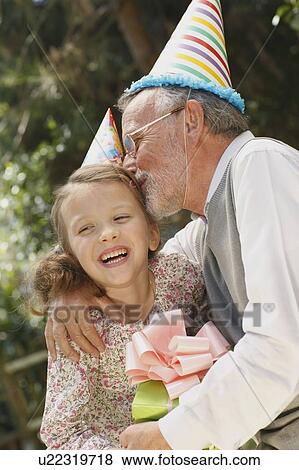 Grandfather kissing grandchild at party View Large Photo Image Stock Photo - Grandfather kissing grandchild at party. Fotosearch