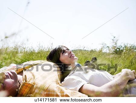 Stock Image - Man and woman lying in grass. Fotosearch