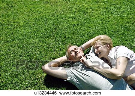 Man and woman lying on grass together View Large Photo Image Stock Photograph - Man and woman lying on grass together. Fotosearch