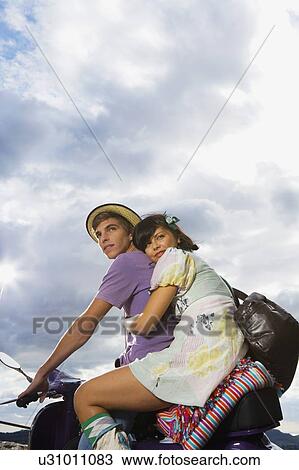 Stock Image - Man and woman on scooter.. Fotosearch
