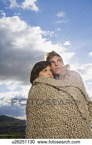 Stock Image - Man and woman wrapped in blanket.. Fotosearch