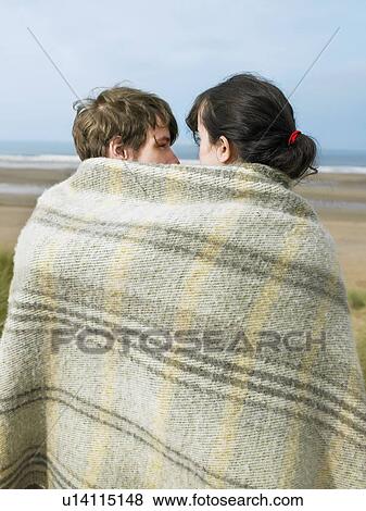 Stock Photo - Young couple wrapped in blanket. Fotosearch