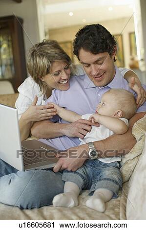 Young family on sofa with laptop View Large Photo Image Stock Image - Young family on sofa with laptop. Fotosearch