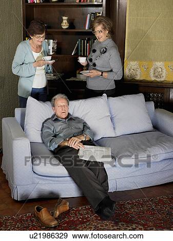 Two senior women drinking tea behind sofa while senior man dozes. Alicante, Spain. View Large Photo Image Stock Photo - Two senior women drinking tea behind sofa while senior man dozes. Alicante, Spain.. Fotosearch