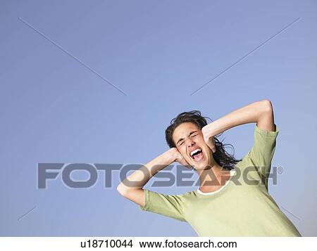 Woman covering ears and screaming outdoors. View Large Photo Image Picture - Woman covering ears and screaming outdoors.. Fotosearch
