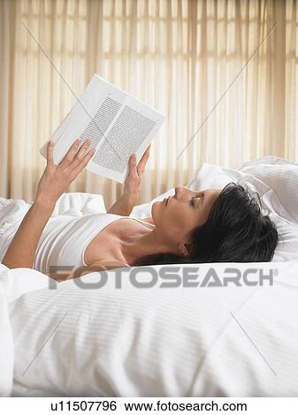 Woman reading a book in bed View Large Photo Image Stock Photograph - Woman reading a book in bed. Fotosearch